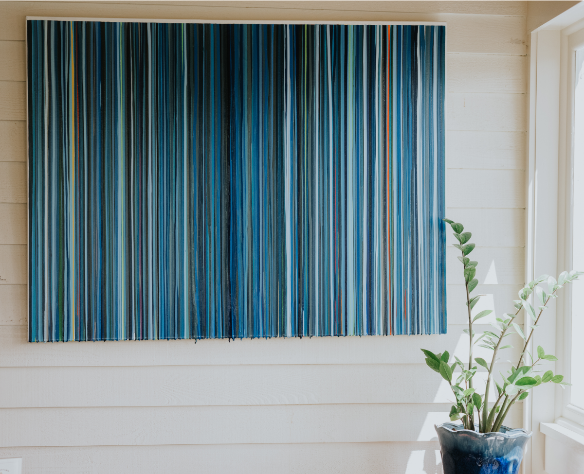 Abstract blue-striped artwork hanging on a wall with a potted plant below at Winvian Farm